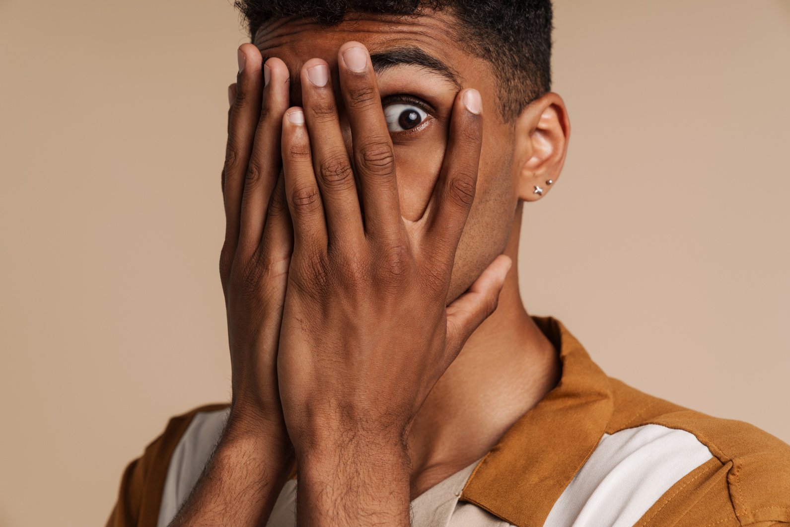 Shocked Black Man Covering His Face and Looking at Camera